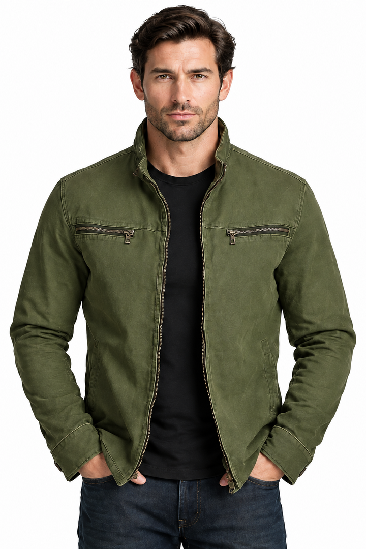 Man against a white background wearing the olive green jacket open over a black tee and dark jeans.