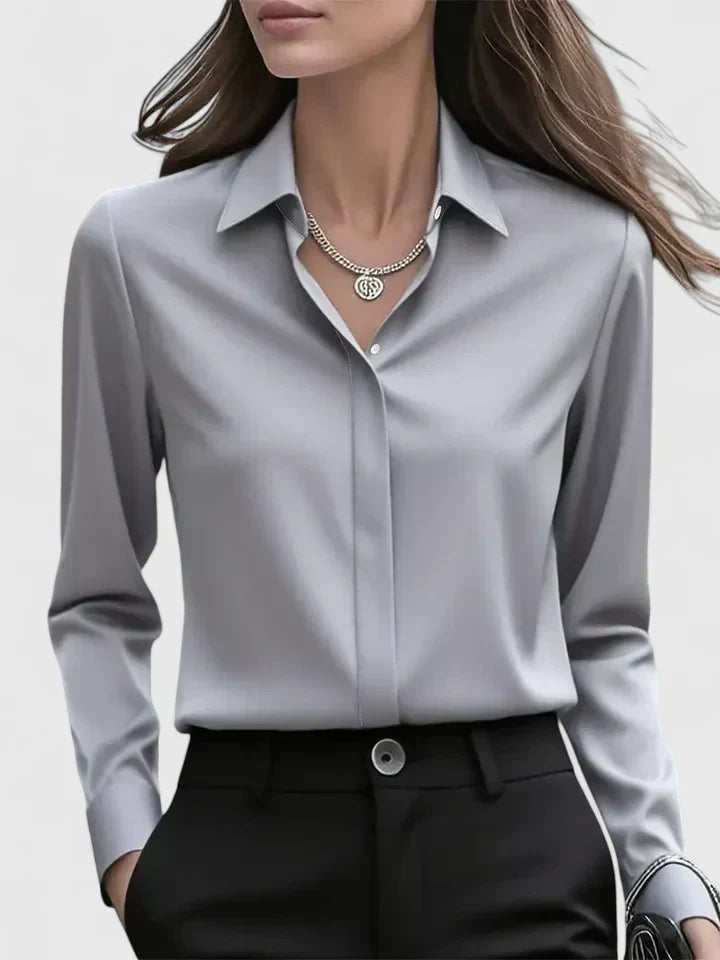Front view of the gray satin blouse with concealed buttons, styled with black trousers and a silver necklace.