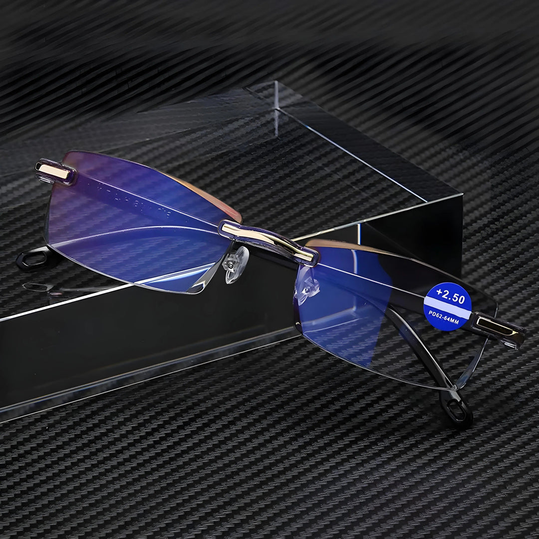 Rimless glasses with blue-reflective lenses and gold hinge accents on a clear acrylic block.