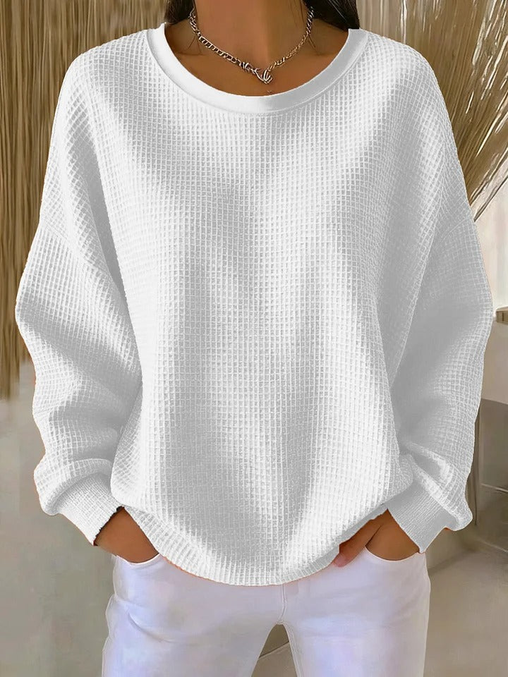 White loose waffle-knit sweater styled with white pants and a silver chain necklace.