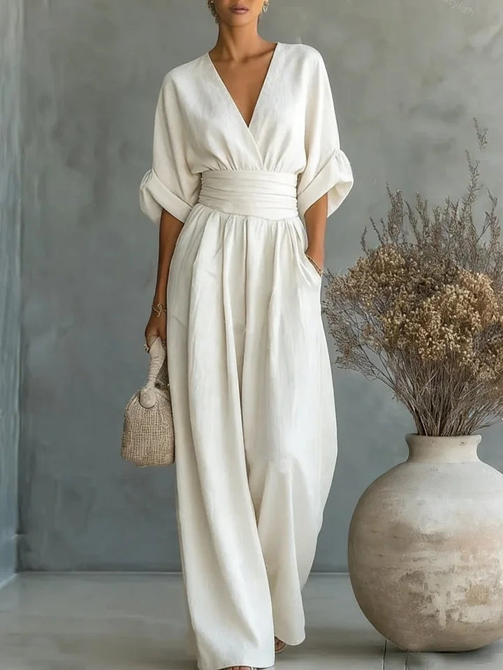 Cream white women's jumpsuit with a wrap neckline, pleated waist and wide legs.