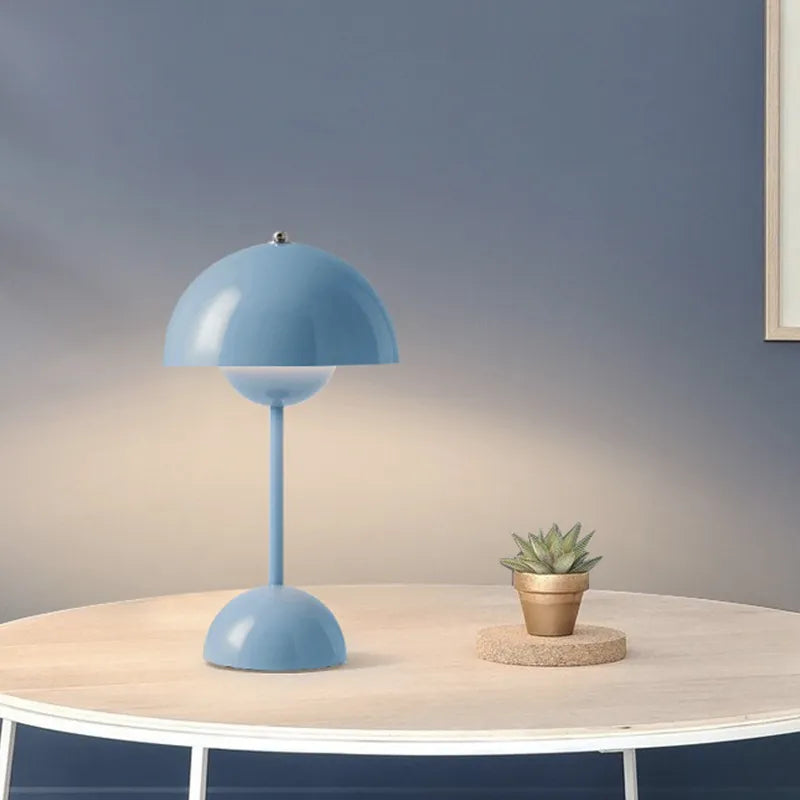 Blue rechargeable USB table lamp lit on a round white table beside a small potted succulent.