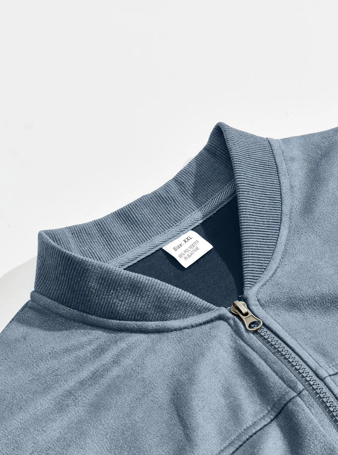 Close-up of the ribbed stand collar and metal zipper of a blue jacket, with inner size label 7