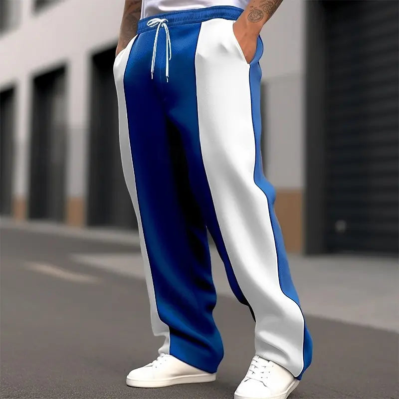Cropped street shot of medium blue and white color-block sweatpants with drawstring waist and white sneakers 7