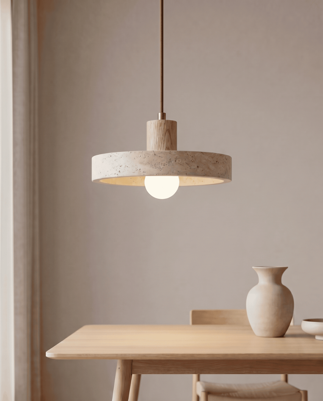 Travertine pendant light with a light oak wood version above a dining table.