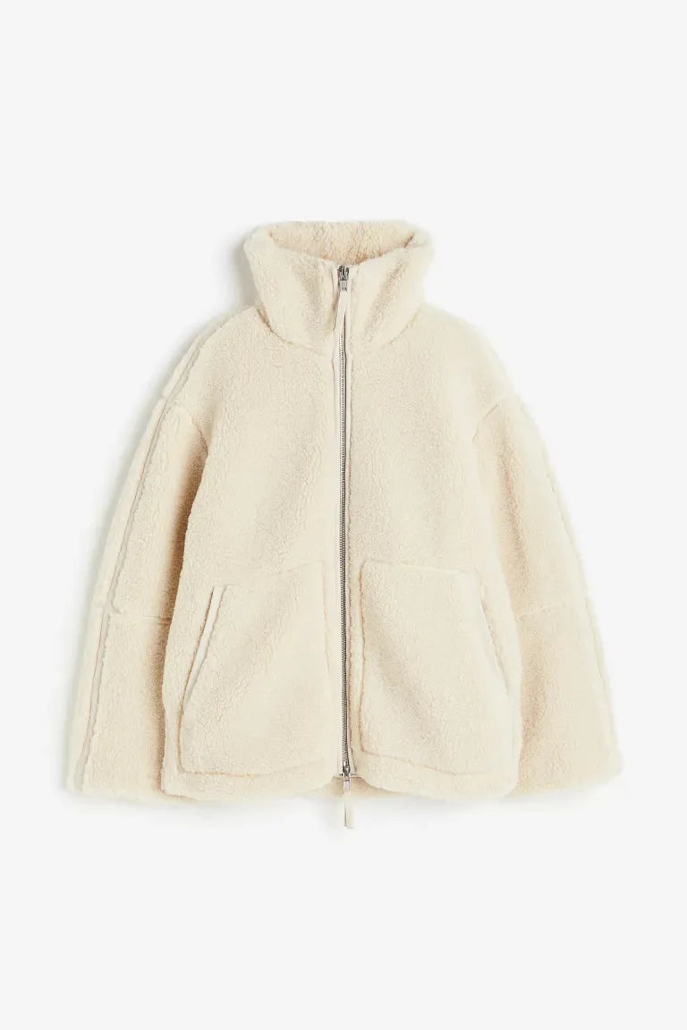 Cream fleece zip coat laid flat, showing the high collar, front patch pockets and silver zipper 7