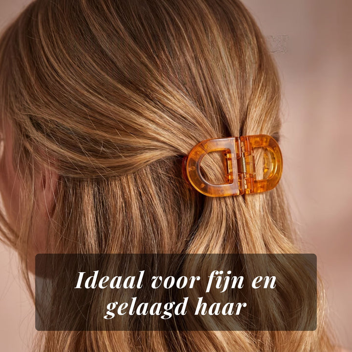 Close-up of an amber translucent Flat Grip Magnetic Hair Clip holding layered hair in a half-up style.