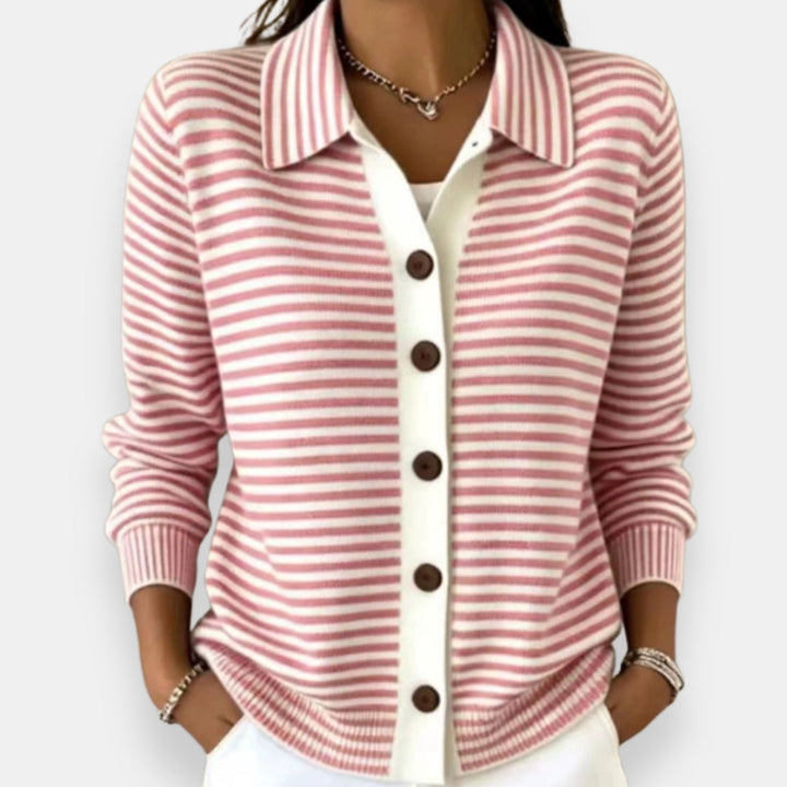 Woman wearing the collared cardigan in pink and white stripes with brown buttons, white placket, ribbed cuffs, hands in pockets. 4