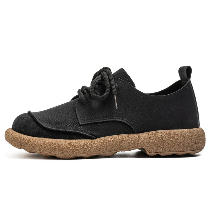 Side view of a black lace-up shoe with suede toe cap and tan sole 7