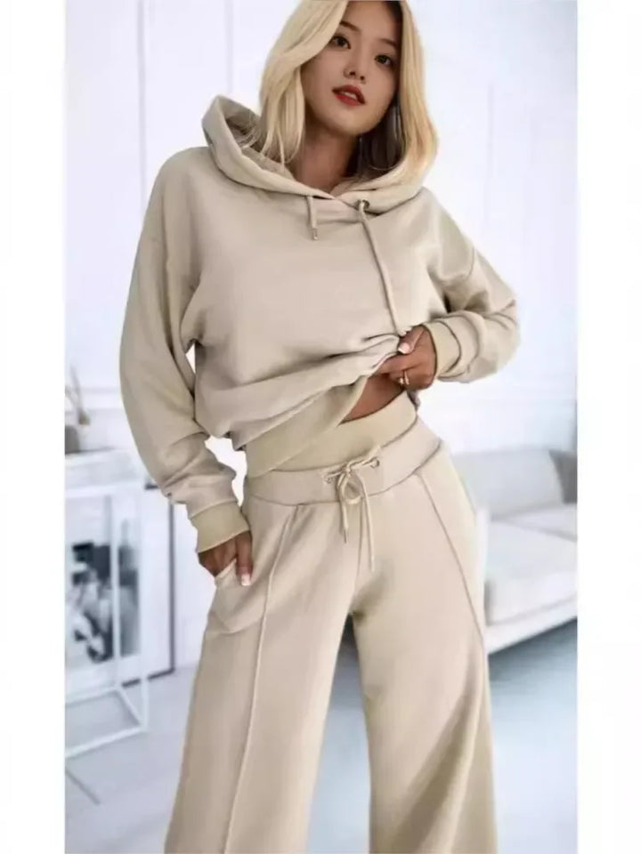 Close three-quarter view of a model in a beige hoodie and ribbed-waist pants, hand in pocket 7