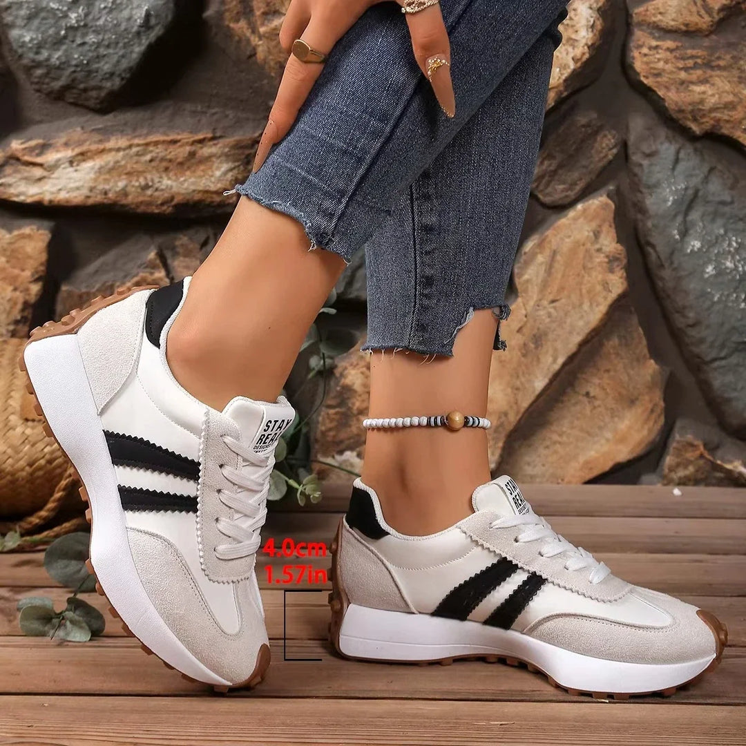 Cream trainers with black stripes worn with frayed jeans, with a measurement mark showing the platform height 7