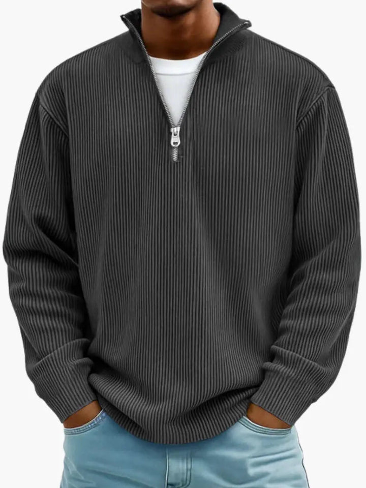 Man wearing the ribbed quarter-zip sweater in charcoal black over a white tee, hands in jeans pockets.