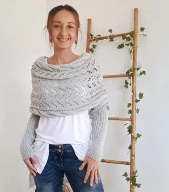 Smiling woman in the pale gray wrap with lace panel and ribbed sleeves, standing next to a ladder with ivy and string lights. 15
