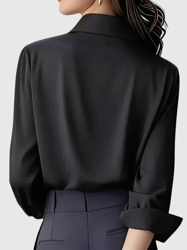 Back view of the black satin blouse on a model, showing the collar and loose fit with cuffs folded back.