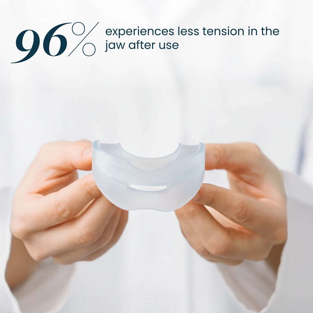 Two hands hold the clear silicone mouthpiece, showing its curved shape and a slot in the front, against a white background. 27