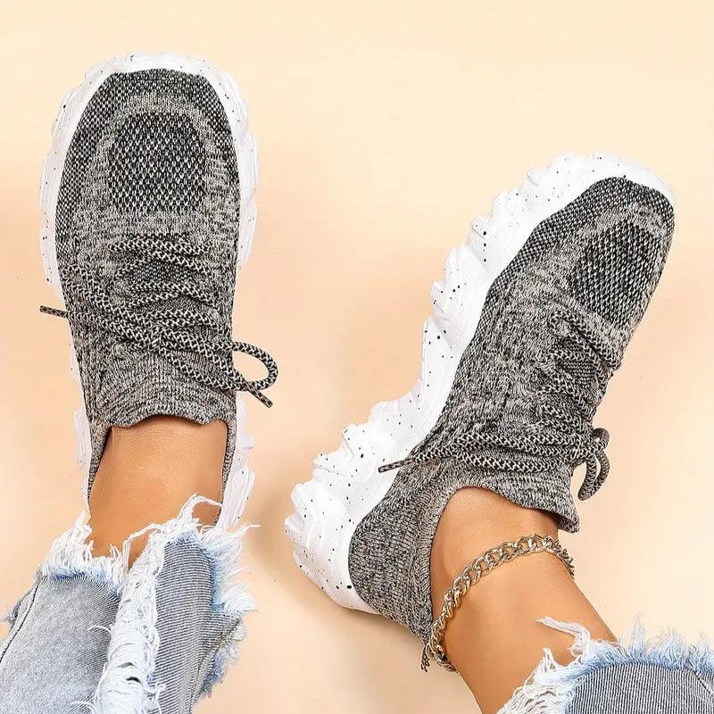 Top-down view of a model's feet in heathered gray knit lace-up sneakers with white speckled chunky soles and ripped jeans. 41