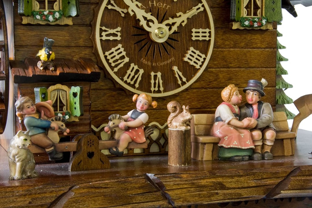 Close-up of the clock base showing a kissing couple on a bench, children on a seesaw and squirrel 13