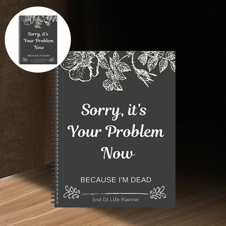 Spiral-bound planner with a dark charcoal cover and white floral line art, standing on a wooden shelf 1