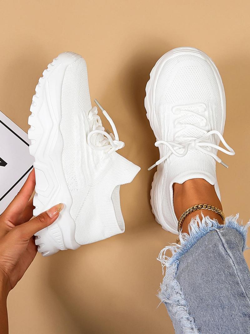 White knit sneakers with white laces and chunky soles, top-down view.