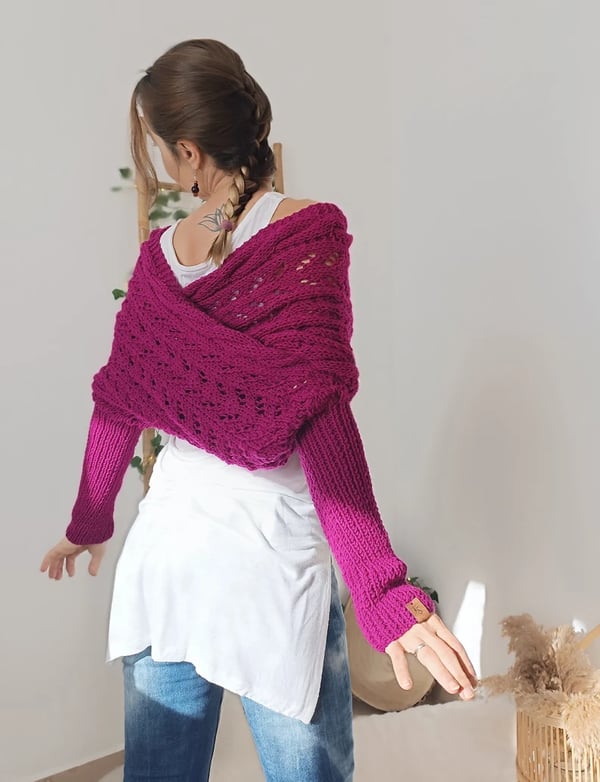 Back view of the magenta wrap crossing over the shoulders, with ribbed sleeves and a small leather tag on one cuff. 11