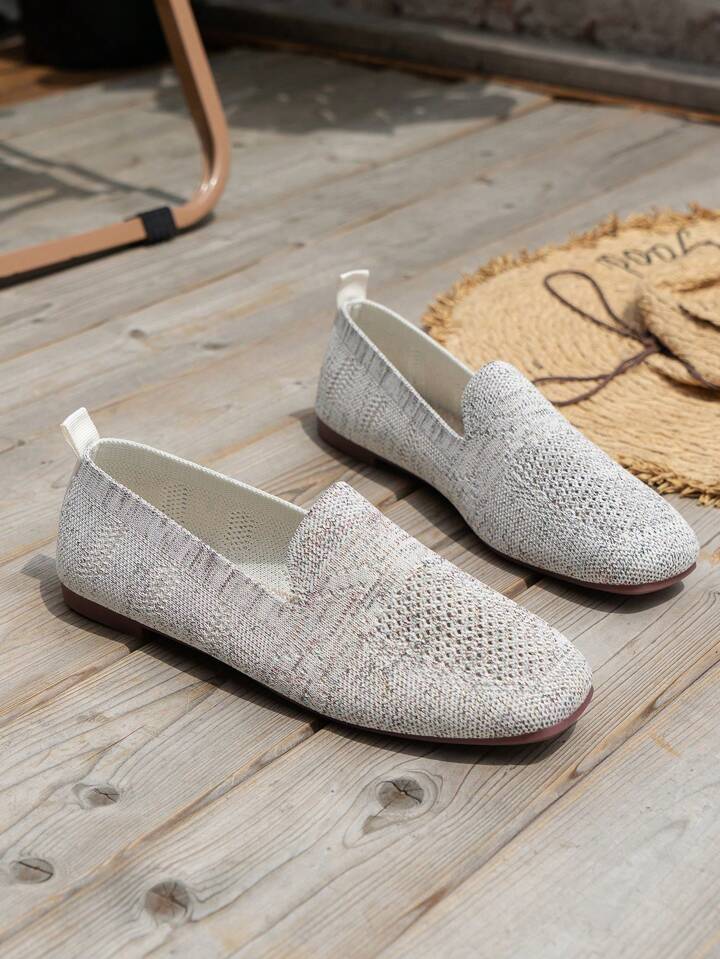 Pair of gray knit slip-on flats with heel pull tabs and brown soles.