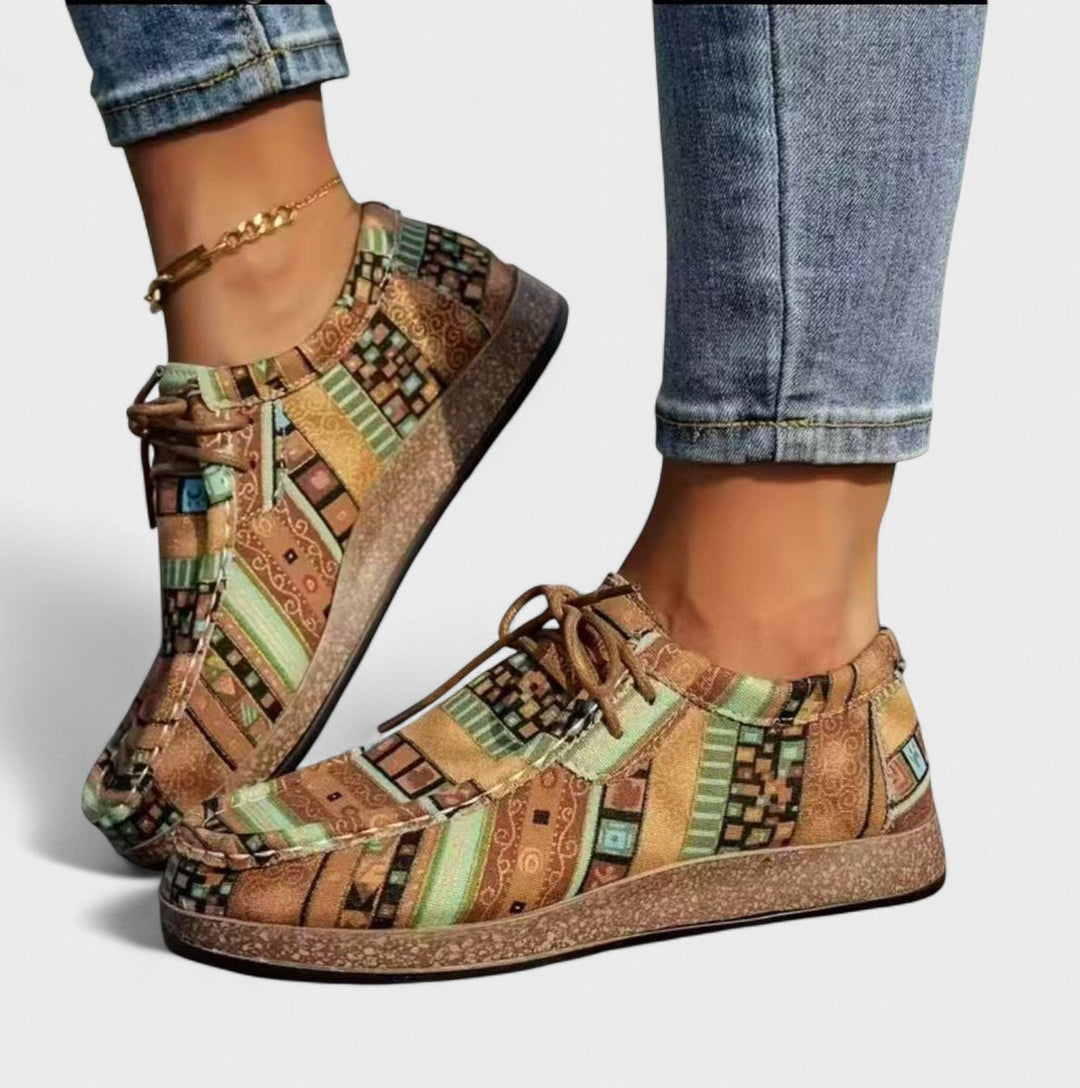 Sneakers in a muted green, tan and brown geometric pattern with brown laces and cork-style soles.