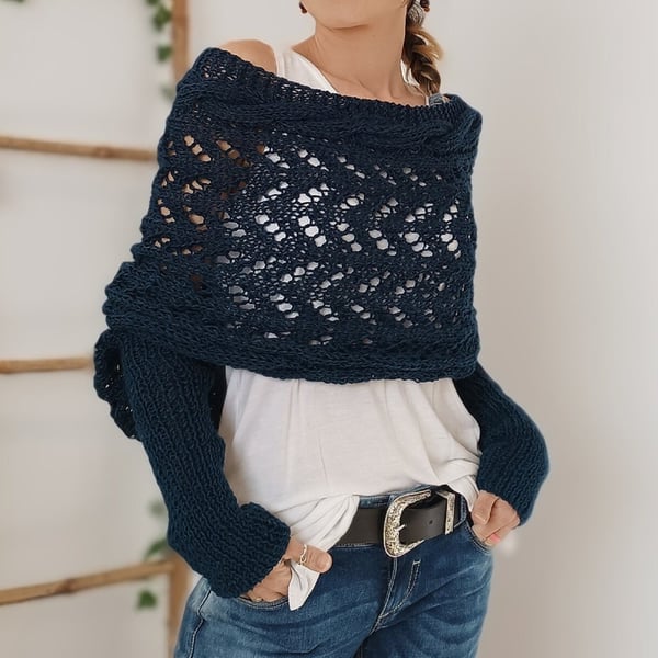 Dark navy lace wrap worn off one shoulder with long ribbed sleeves, hands in jeans pockets and a black belt at the waist. 16