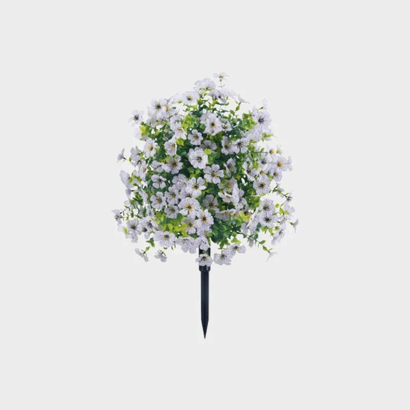 White artificial flower bush with light green leaves on a black ground stake against a plain gray background.