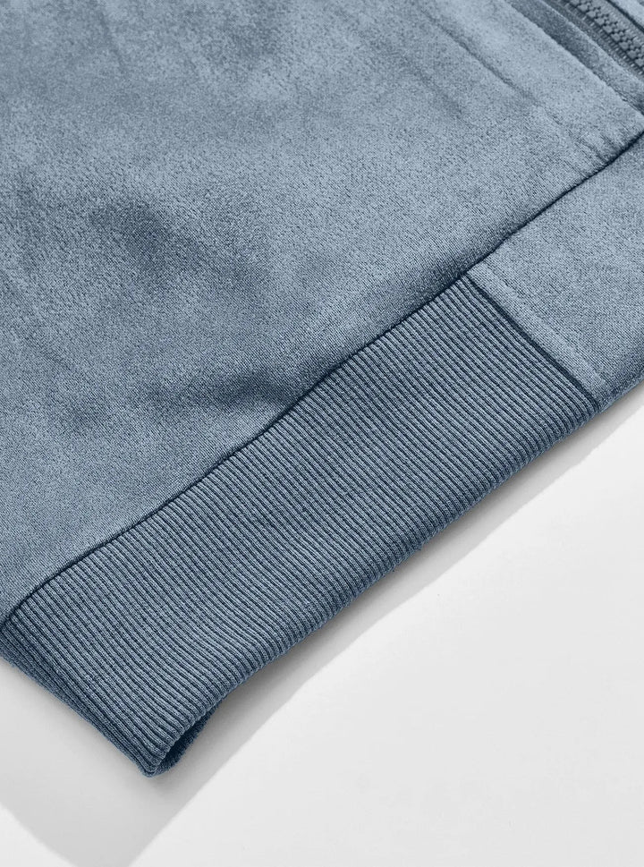 Close-up of the ribbed bottom hem of the blue jacket against the soft suede-look fabric 8