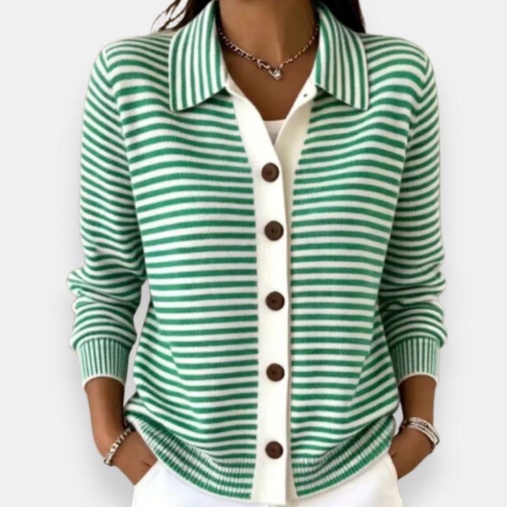 Woman wearing the collared cardigan in green and white stripes with brown buttons, white placket, ribbed cuffs, hands in pockets. 2