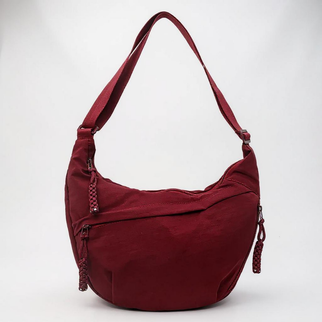 Burgundy red nylon shoulder bag with adjustable strap and braided zipper pulls, detail.