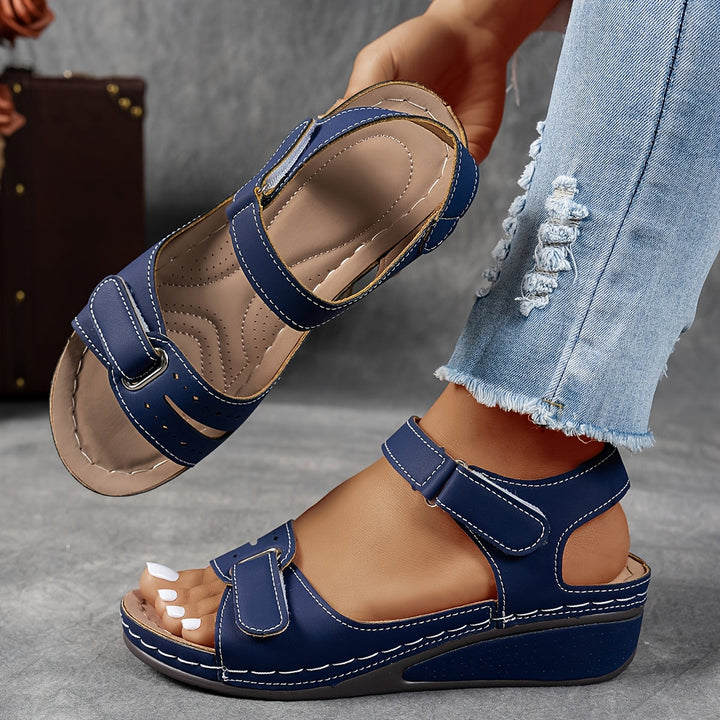 Navy blue wedge sandal with white stitching and adjustable straps, with the insole visible. 8