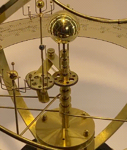 Detail of the brass gear train and central shafts driving a polished sphere and planet arms.