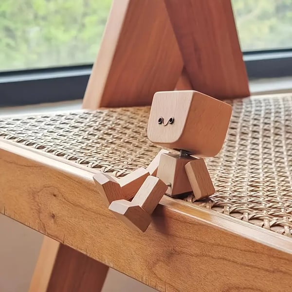 Wooden figure with a smiling face sits on the edge of a rattan-seat wooden chair 11
