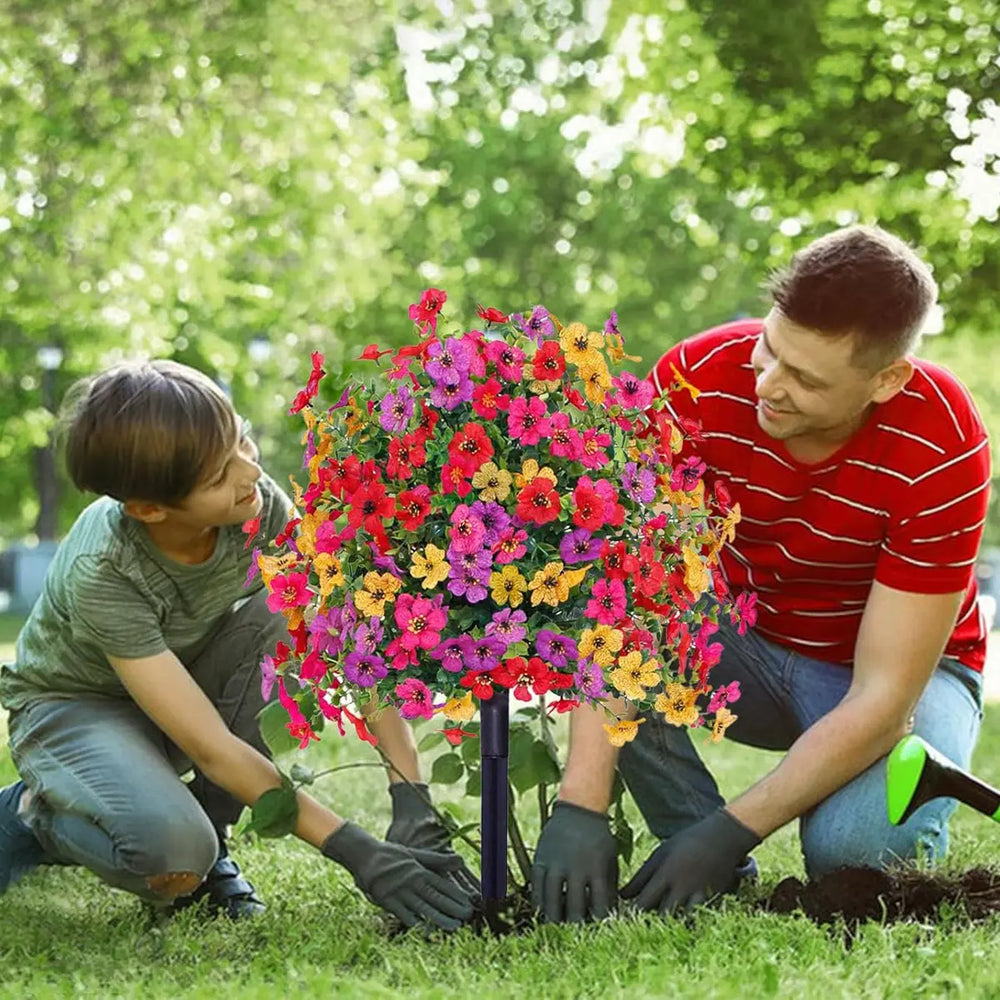 Multicolor artificial flower bush detail with red, pink, purple and yellow blooms in a garden setting.