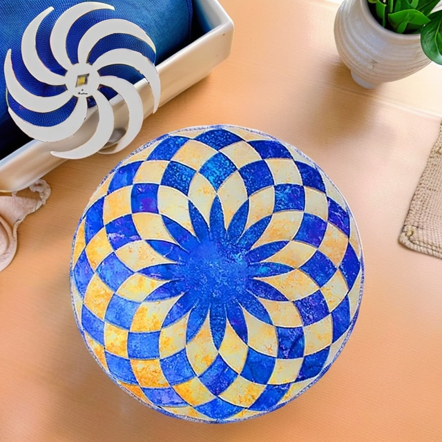 Overhead view of a round placemat with a blue and cream pinwheel pattern on a peach table.