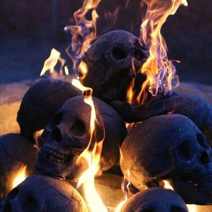 Another view of stacked skulls with cracked, weathered surfaces and orange and violet flames.