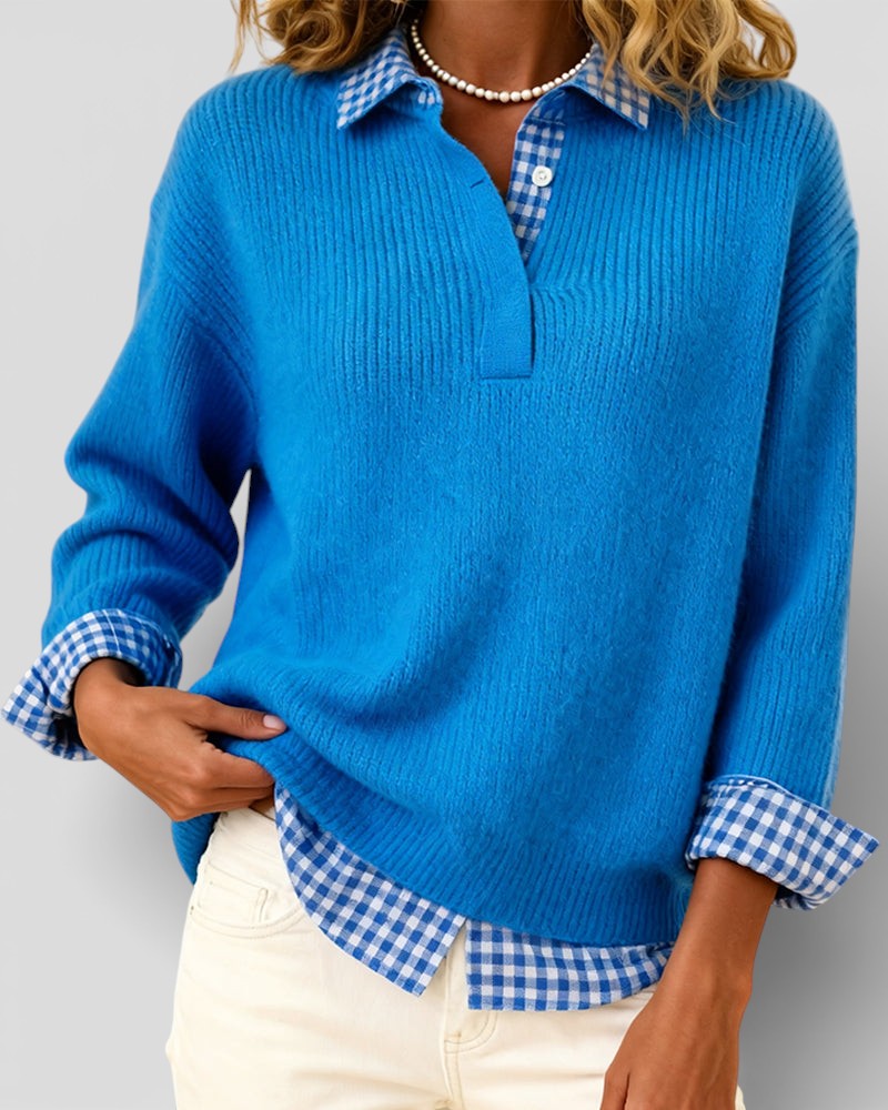 Blue ribbed knit sweater detail with one hand at the hem and gingham shirt showing beneath.