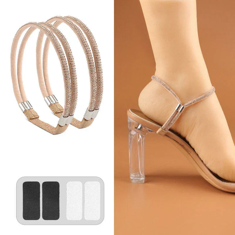 Pair of nude beige crystal-studded elastic shoe straps with adhesive pads holding the heel of a clear-heeled sandal.