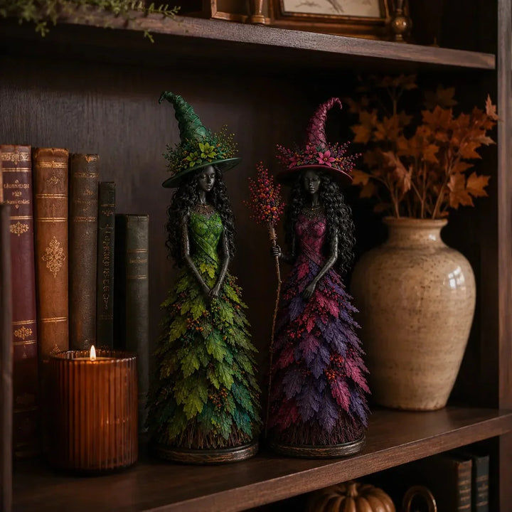 Green and purple-magenta witch figurines on a dark bookshelf beside old books, a glowing candle and a vase of autumn leaves. 4