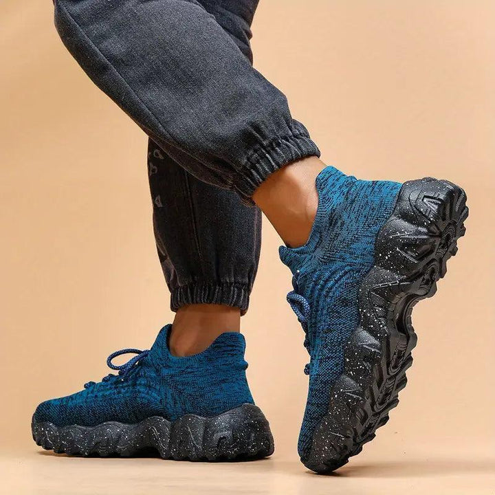 Person in blue knit sneakers with black speckled soles, one foot raised to show the thick sole from the side. 30
