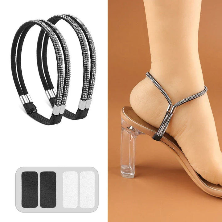 Pair of black elastic shoe straps with sparkling crystal rows and adhesive pads secured around a heel in a clear-heeled sandal.