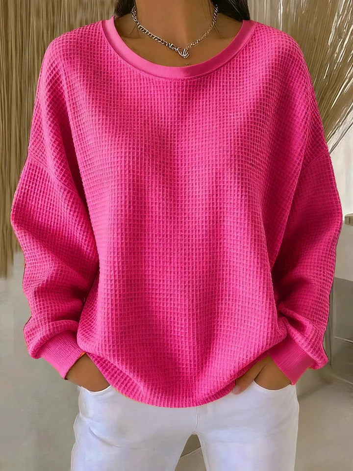 Hot pink waffle-knit crew neck sweater with ribbed cuffs and hem and white pants.