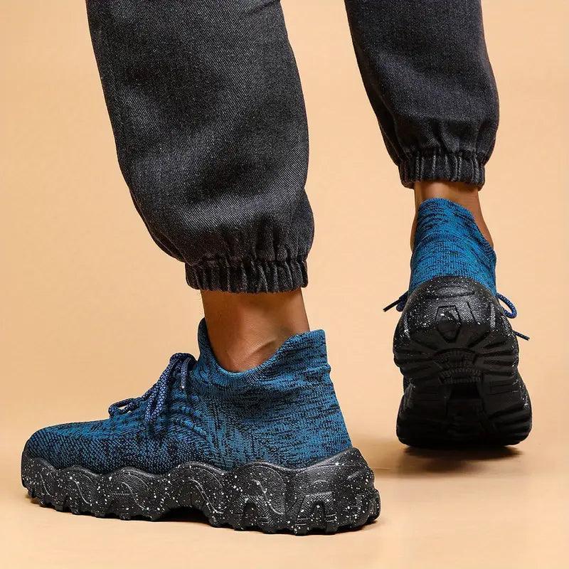 Rear view of a person walking in blue knit sneakers with black speckled soles, with the lifted shoe showing its tread. 29