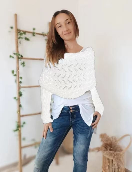 Woman wears the white lace-knit wrap with ribbed sleeves over a white top and jeans, one hand in her pocket. 17