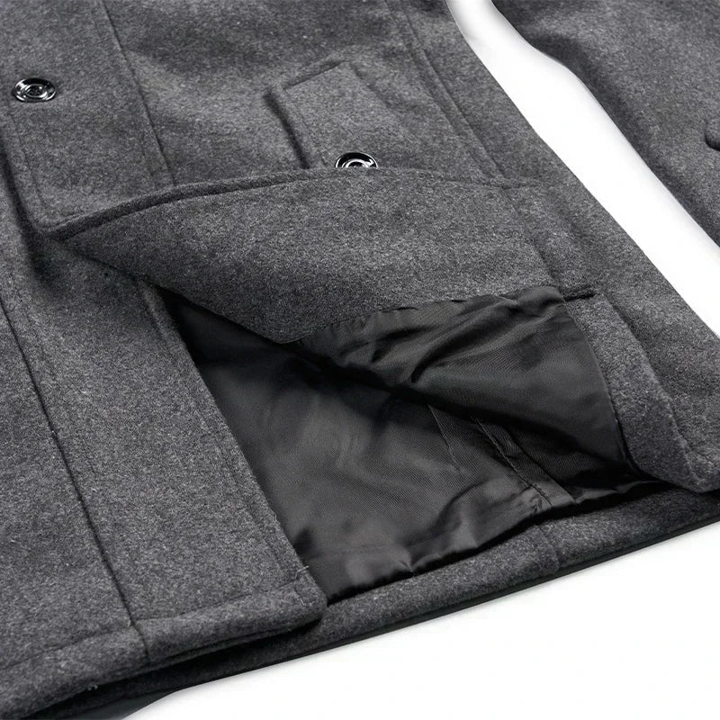 Close-up of a gray coat pocket flap lifted to show the black lining beneath 9