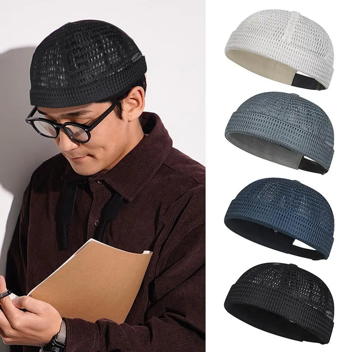 Man with round glasses and a black mesh cap reading a notebook, beside four colors of the cap 9