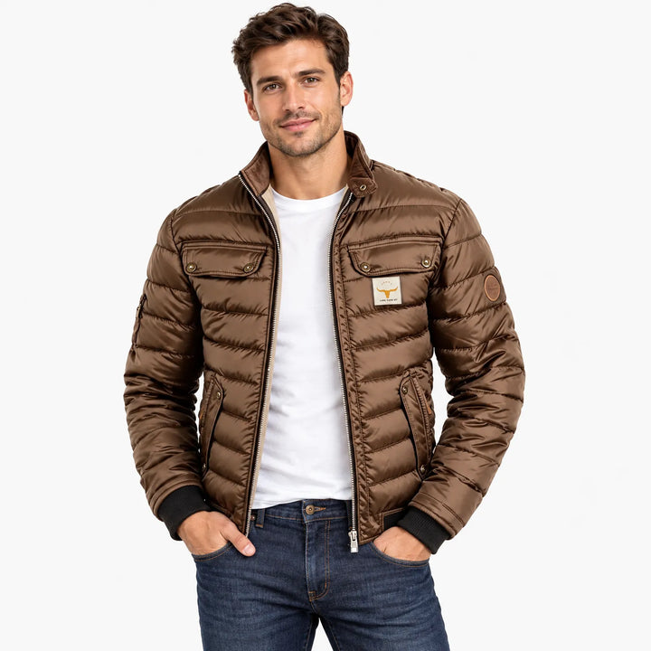 Smiling man wearing the brown quilted jacket open over a white tee and dark jeans 9