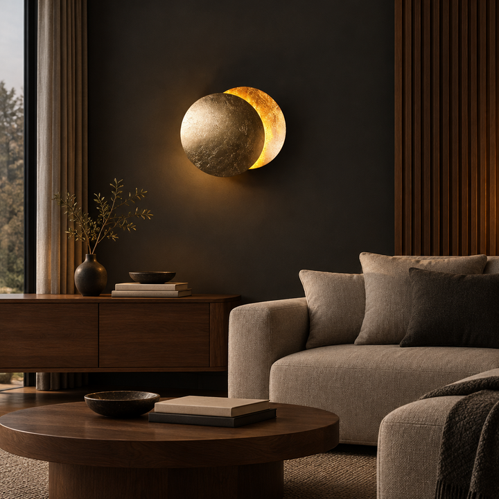 Gold-leaf disc wall lamp glowing on a dark wall above a wooden sideboard and beige sofa 1
