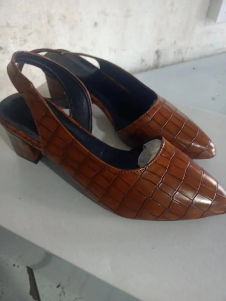 Pair of brown croc-embossed pointed slingbacks with block heels on a white surface, angled view 9